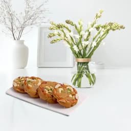 Bikanervala Halwa Sohan with a Rajnigandha Stems in a Glass Vase 1
